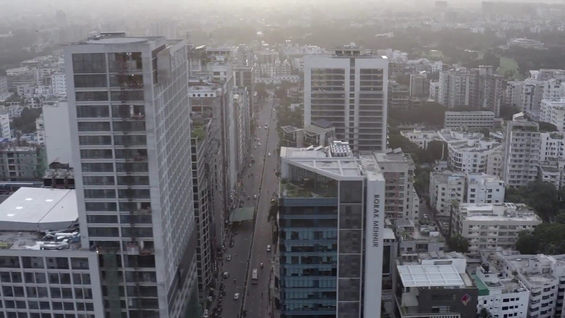 Drone view of a Banani avenue lined with modern towers, one with a rooftop garden