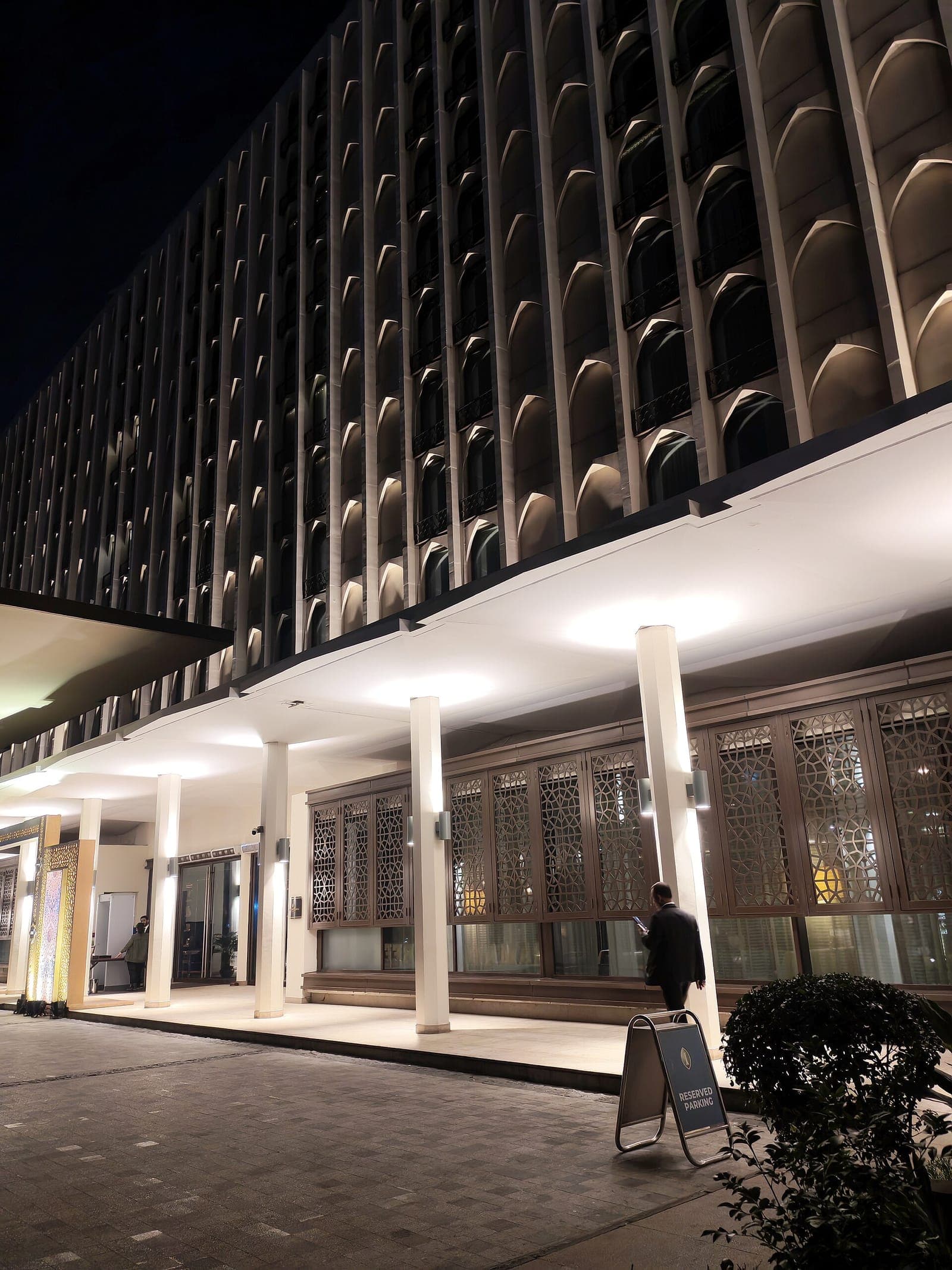 Well-lit modern building entrance in Dhaka at night with patterned screens